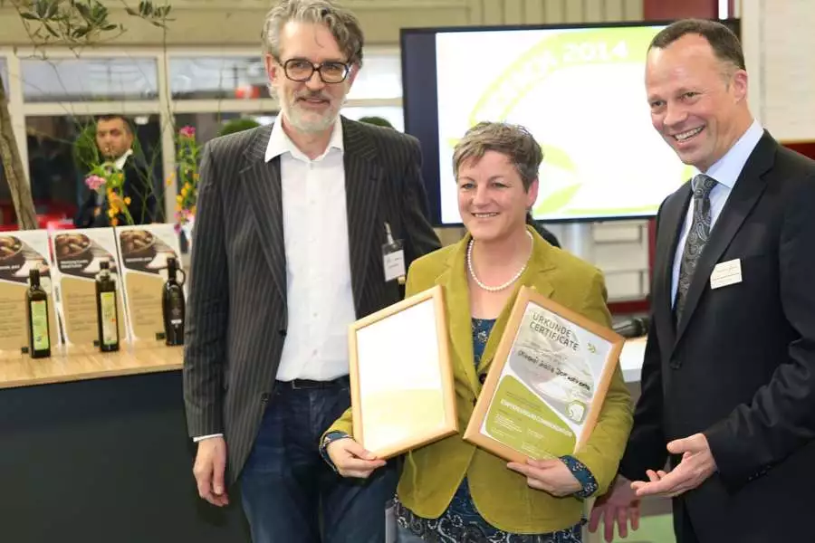 Mit Freude nimmt Eva Kiene (Mitte) die Auszeichnung der Rapunzel Olivenöle auf der BioFach von Richard Wolny (links) und Udo Funke (rechts) entgegen.