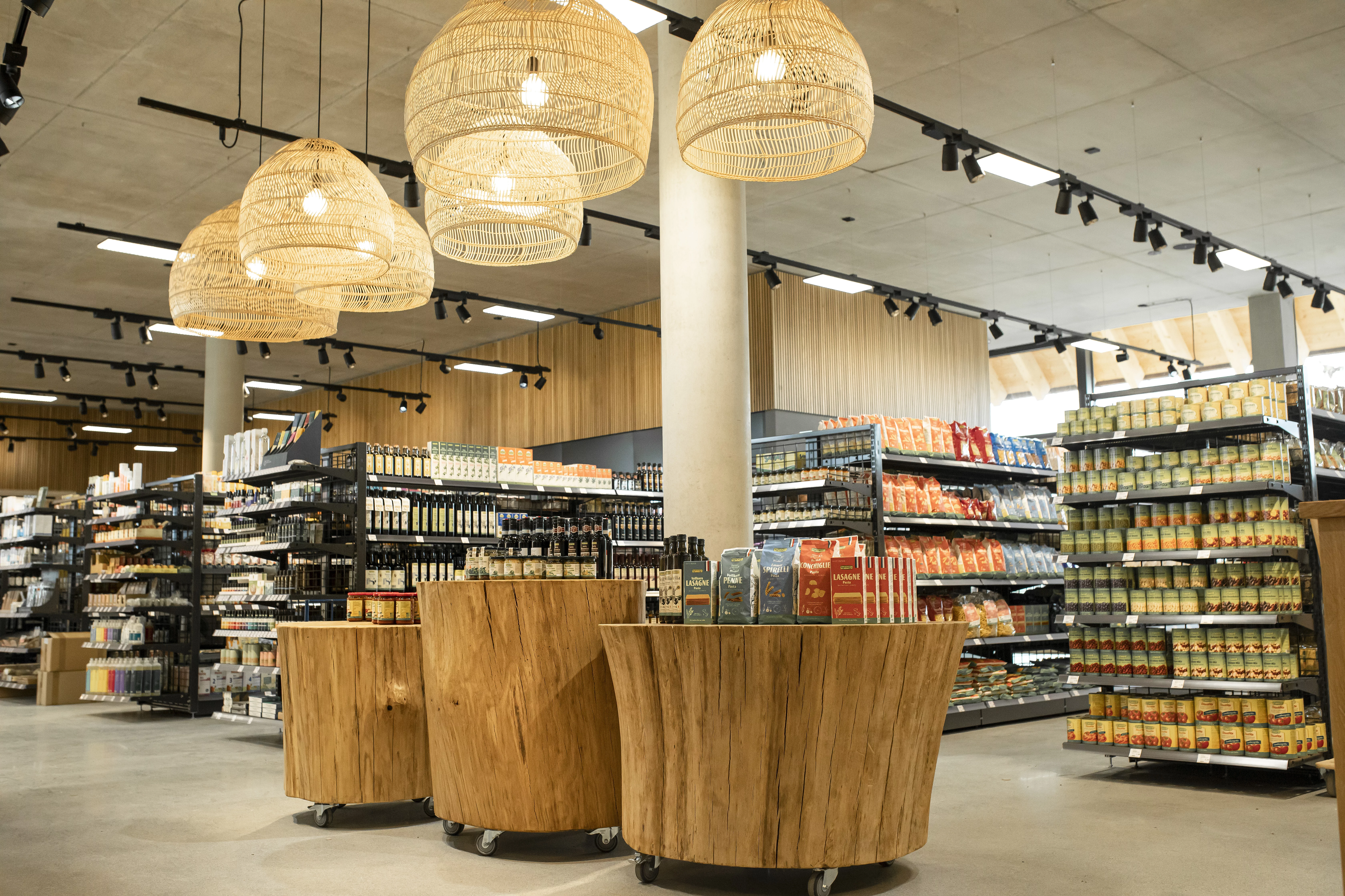 Drei Präsentationsflächen mit Produkten, im Hintergrund weitere mit Rapunzel Produkten gefüllte Regale im Bio-Markt der Rapunzel Welt