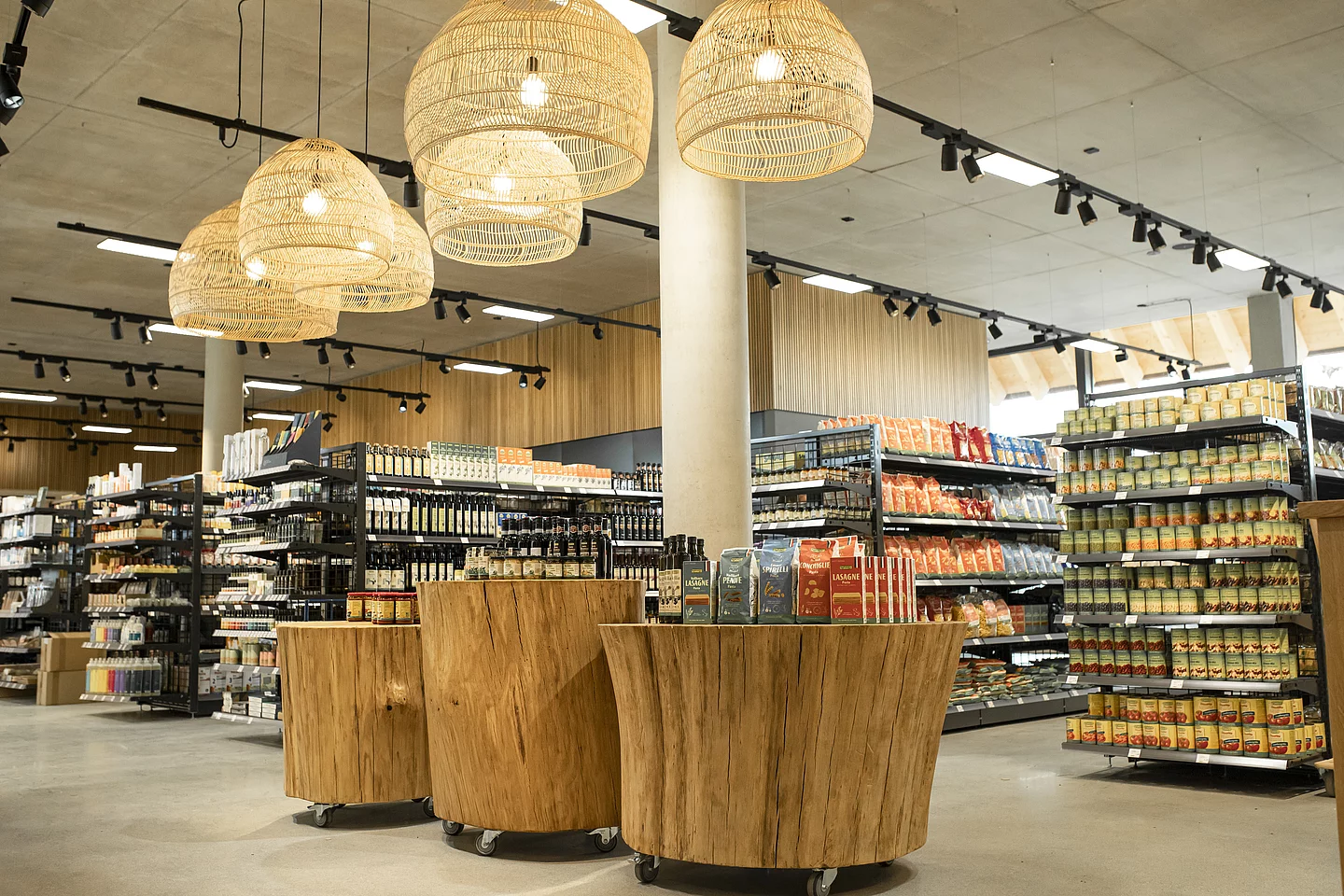 Drei Präsentationsflächen mit Produkten, im Hintergrund weitere mit Rapunzel Produkten gefüllte Regale im Bio-Markt der Rapunzel Welt
