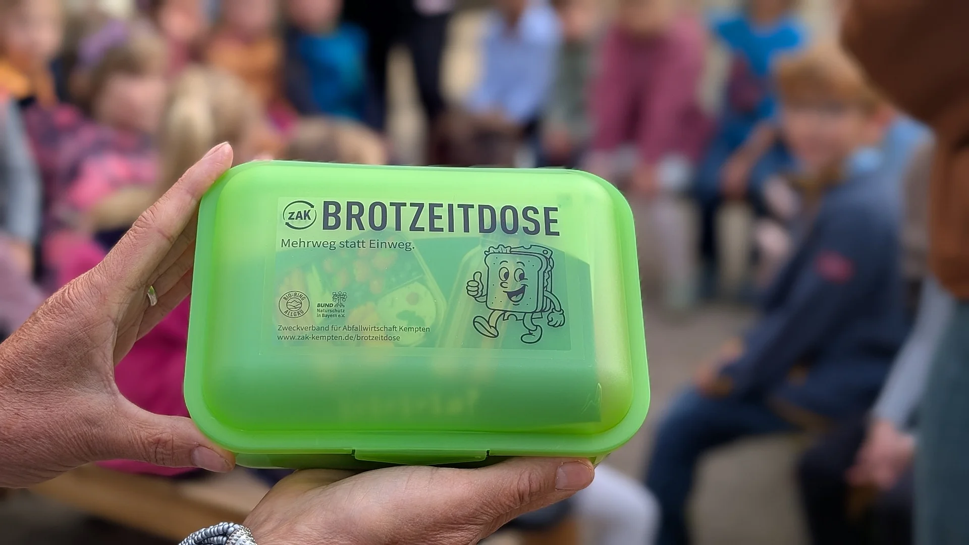 Grüne Brotdose aus der Allgäuer Btortdosenaktion in der Hand