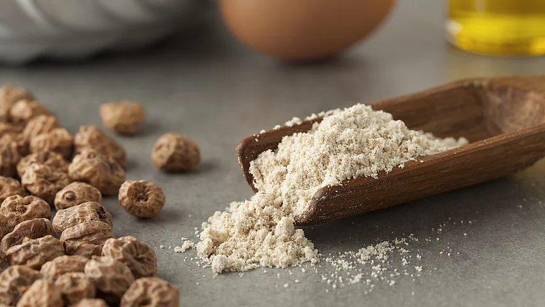 Gemahlene Erdmandeln auf Löffel neben ganzen Erdmandeln, gut geeignet für basenbetonte Rezepte.
