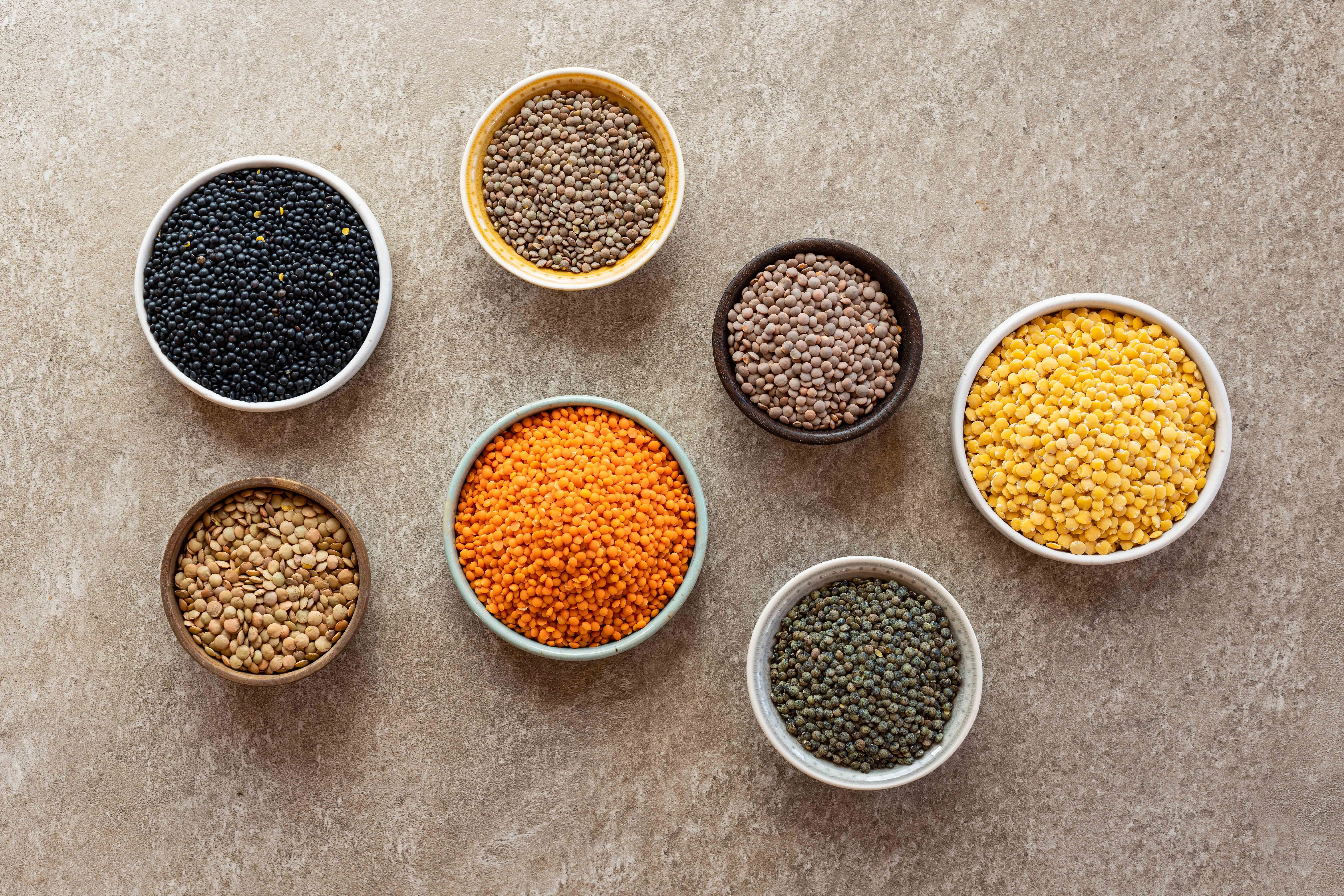 Verschiedene Linsensorten als Rohware – von roten und grünen Linsen bis Belugalinsen. Stimmungsvolles Arrangement mit weiteren Hülsenfrüchten als Übersicht