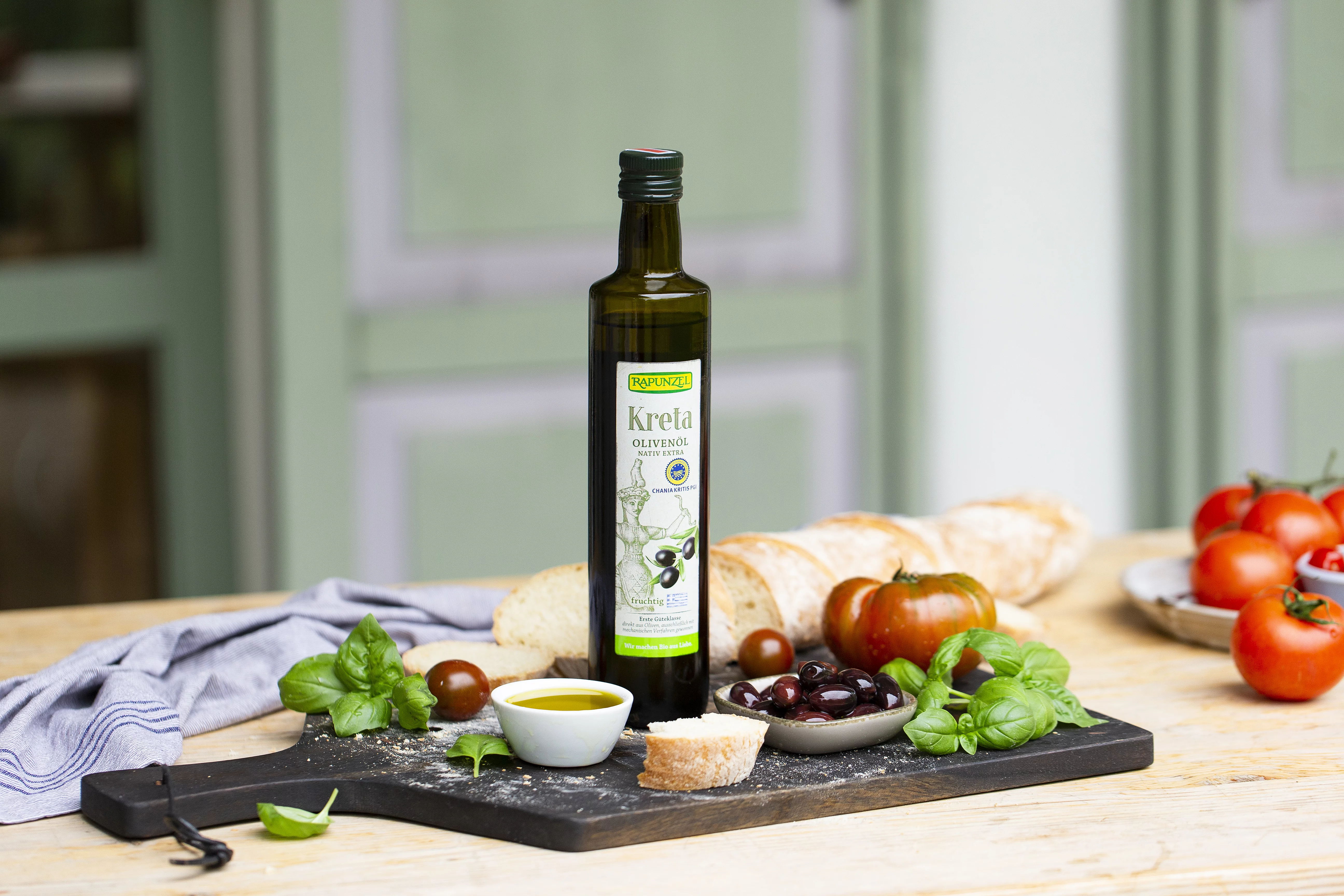 Dass Kreta Olivenöl steht auf einem Tisch im freien. Auf dem Tisch stehen kleine Mezzeteller mit Antipasti und Gemüse