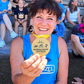 Simone Walter lacht in die Kamera mit ihrer Goldmedaille in der Hand.