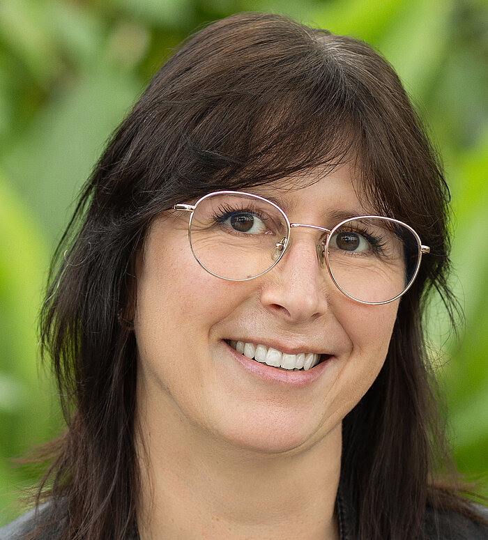 Rapunzel Mitarbeiterin steht vor blühender Pflanze.