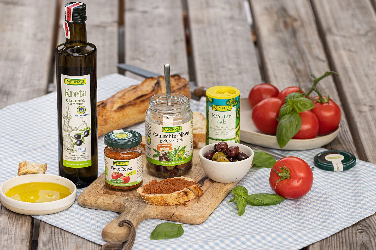 Stimmungsvolles Antipasti-Arrangement mit gemischten Oliven, Pesto Rosso und einer Flasche Kreta-Olivenöl, dekorativ angerichtet auf einem Tisch