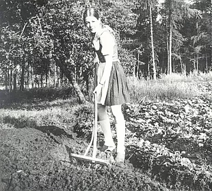 Historisches Foto von Jennifer Vermeulen auf dem eigenen Acker mit Rechen.