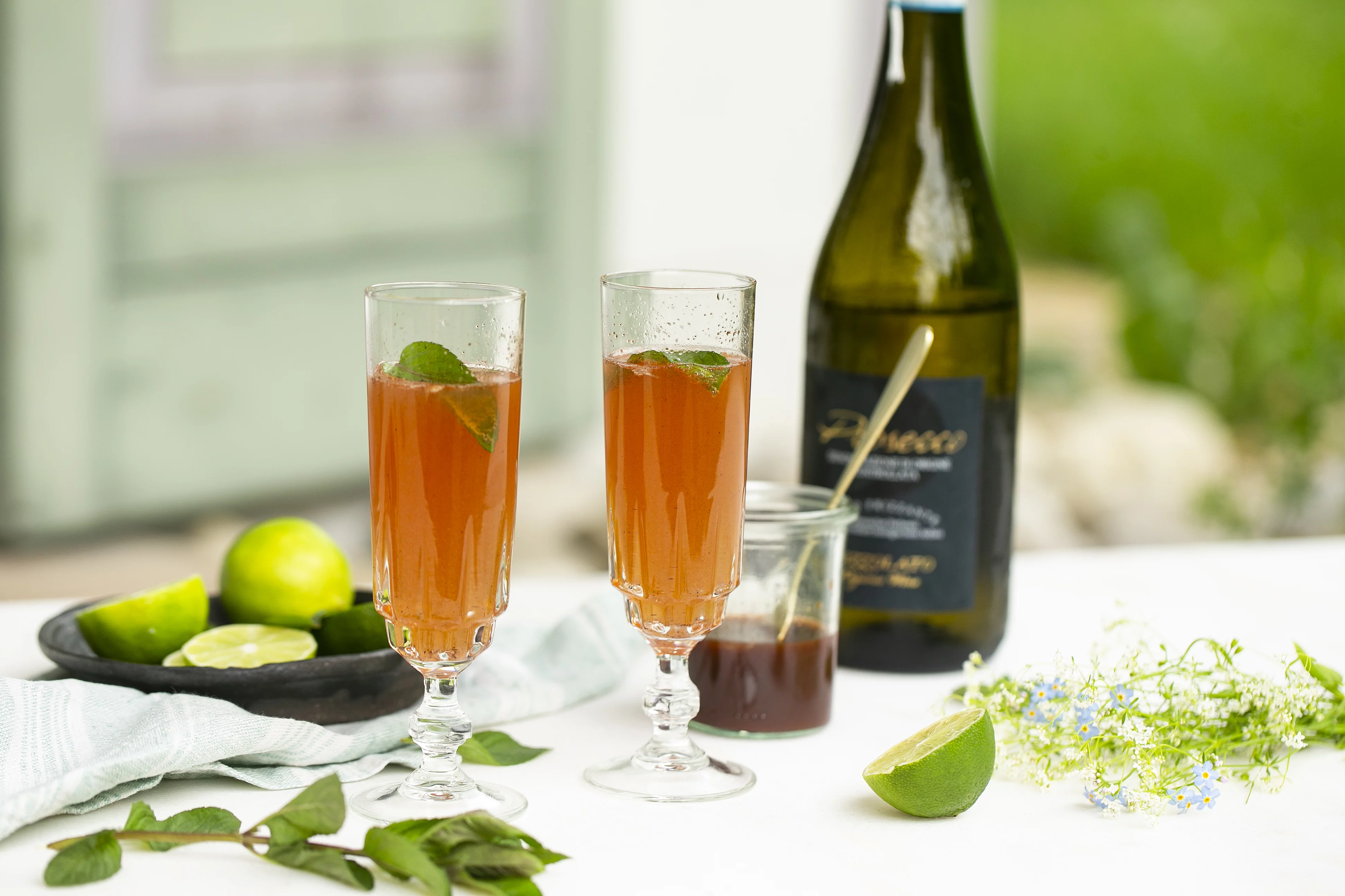 Prosecco von Rapunzel auf tisch im Freien, abgefüllt in Gläser mit Limette verfeinert