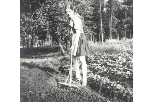 Historisches Foto von Jennifer Vermeulen auf dem eigenen Acker mit Rechen.