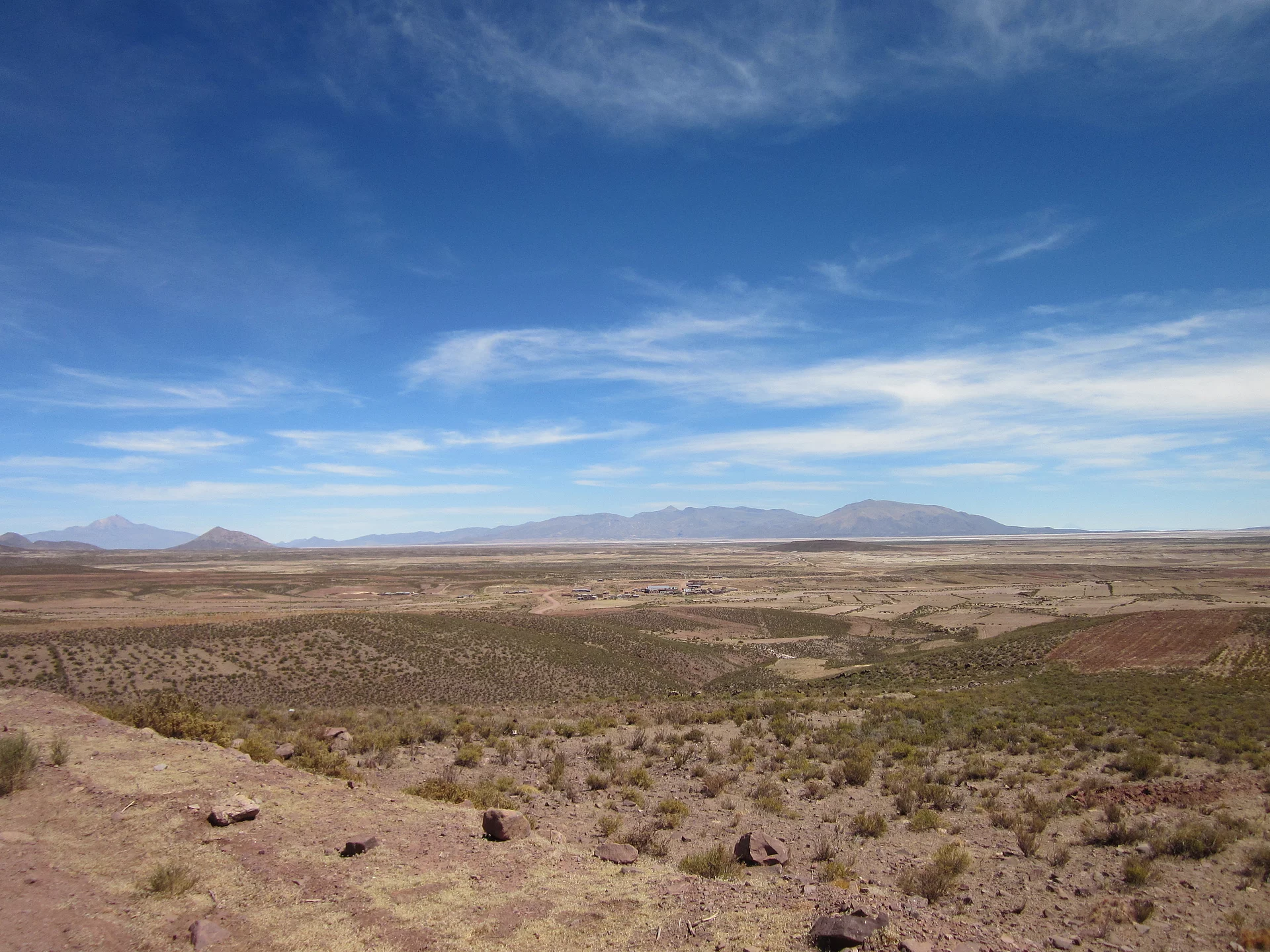 Hochland von Altiplano Sur. Hochland mit brauner Erde und Berge im Hintergrund, blauer Himmel.