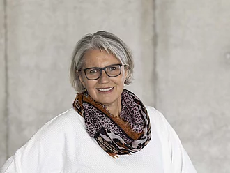 Margit Epple, Rapunzel Geschäftsführerin steht lächelnd vor grauer Betonwand. Sie ist seit 2012 in der Geschäftsführung