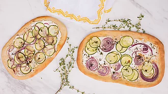 Zwei Pizzen mit Ziegenkäse, Zucchini und Lupinenmehl von oben fotografiert