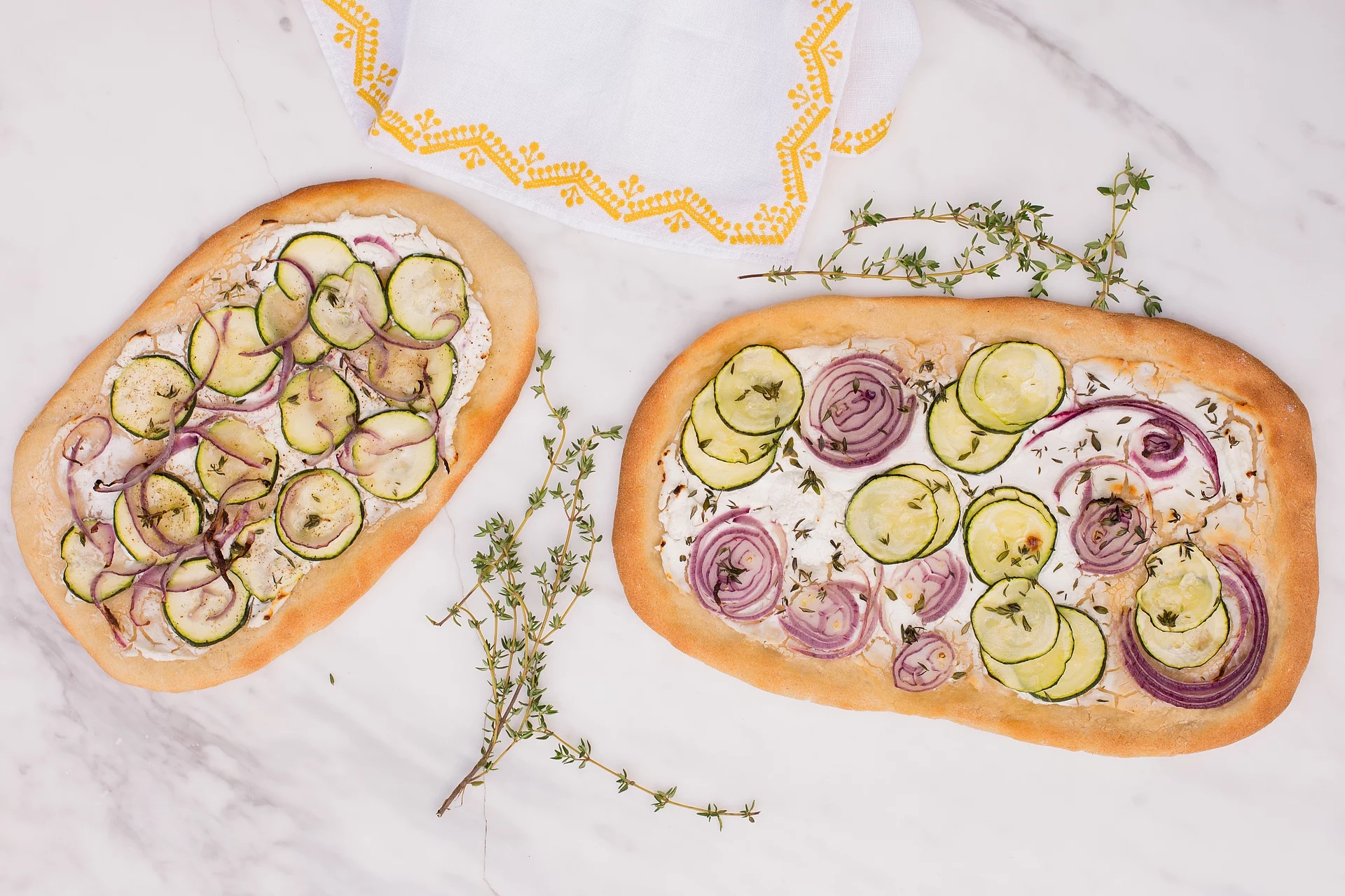 Pizza mit Ziegenkäse und Zucchini und Lupinenmehl Zwei Pizzen mit Ziegenkäse, Zucchini und Lupinenmehl von oben fotografiert