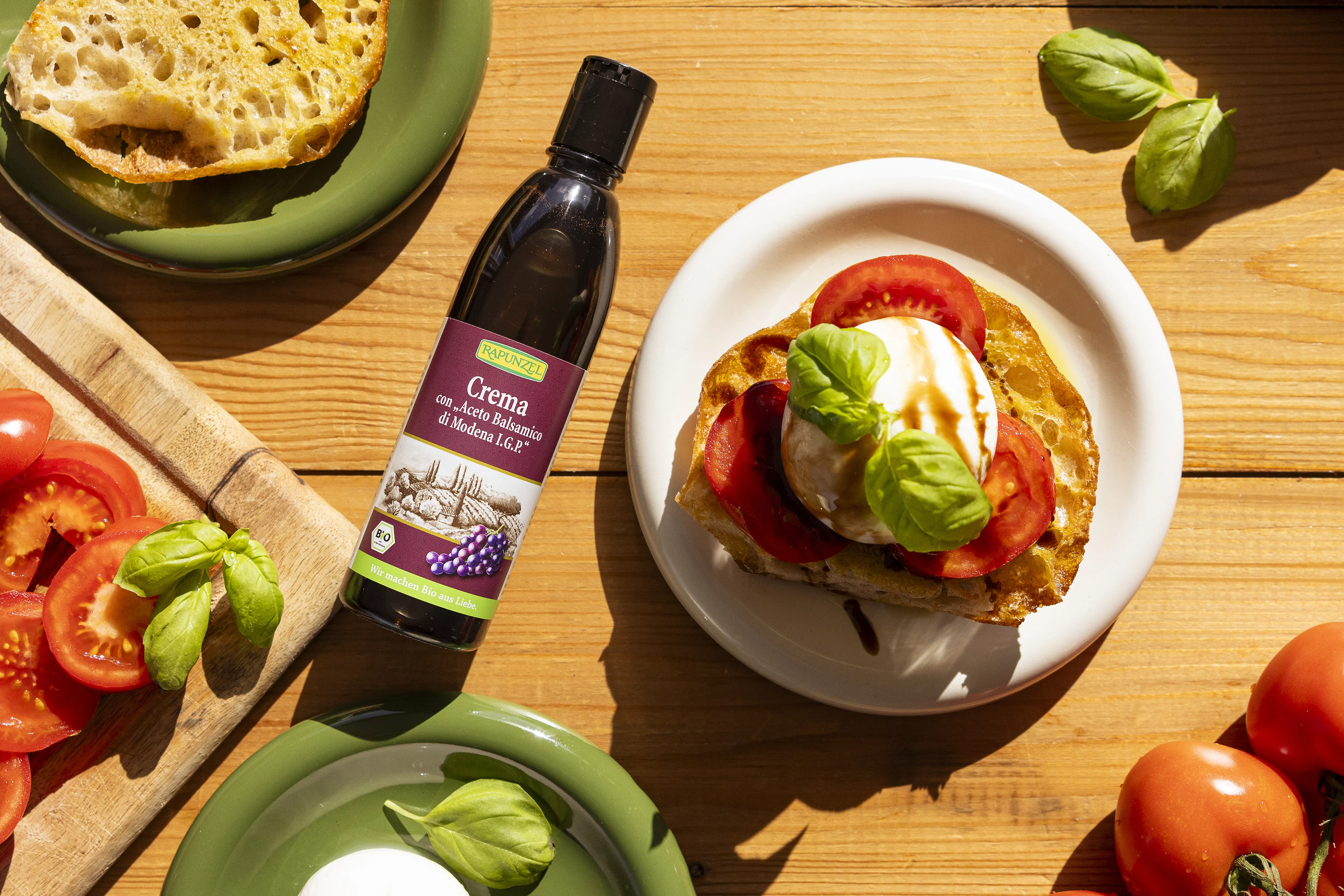 Baguette mit Burrata und Tomate neben einer Flasche Rapunzel Crema con 'Aceto Balsamico di Modena I.G.P.'