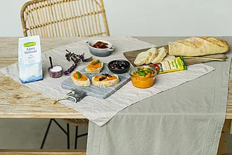 Gedeckter Tisch mit Broten mit Tomatenmark-Butter, daneben eine Packung Steinsalz