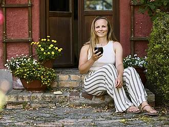 Kaffeegenuss in Bio-Qualität Junge Frau mit Kaffee in sommerlicher Atmosphäre vor einer rustikalen Tür