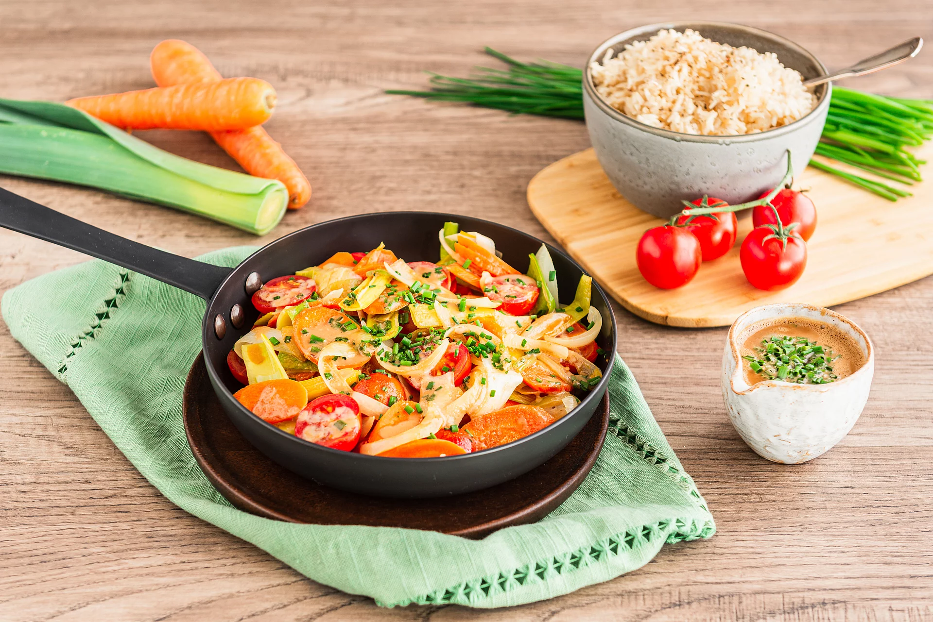 Naturreis enthält Mineralstoffe, Vitamine, ungesättigte Fettsäuren und Ballaststoffe. Gericht Gemüse mit Mandelsauce an Himalaya Basmati Reis Natur in einer Pfanne, daneben ein Teil der Zutaten.