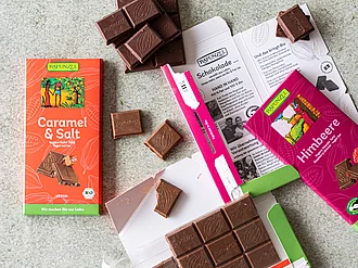 Auf einem Tisch liegen mehrere Sorten veganer Rapunzel Schokolade.