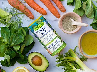 Salz rundet viele Gerichte ab Rapunzel Salz in runder Verpackung inmitten von Gemüse in Vorbereitung auf ein Gericht