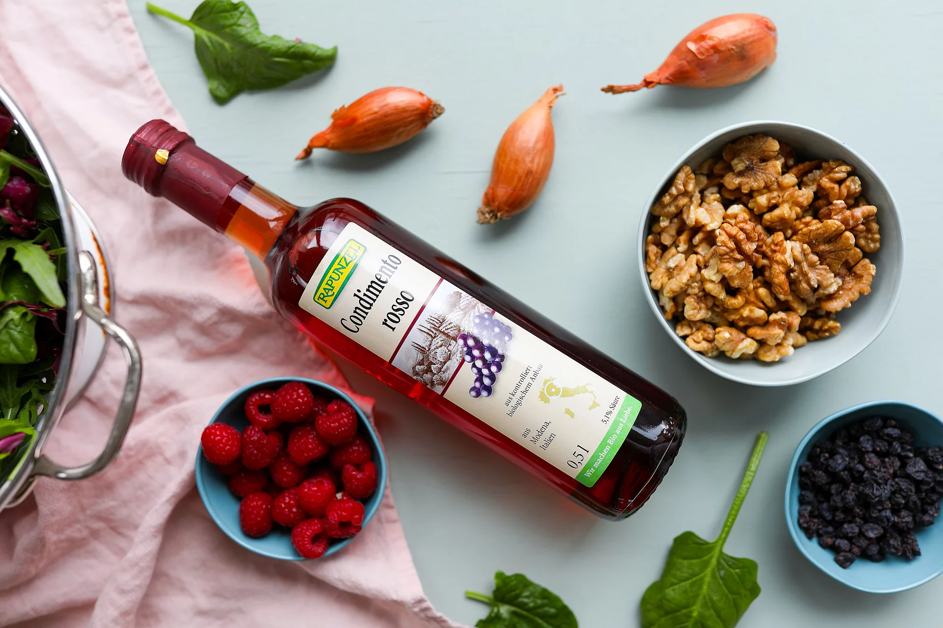 Condimento Rosso mit Nüssen und Früchten Rapunzel Condimento Rosso auf einer Küchenplatte umringt von Schüsseln mit Beeren und Nüssen