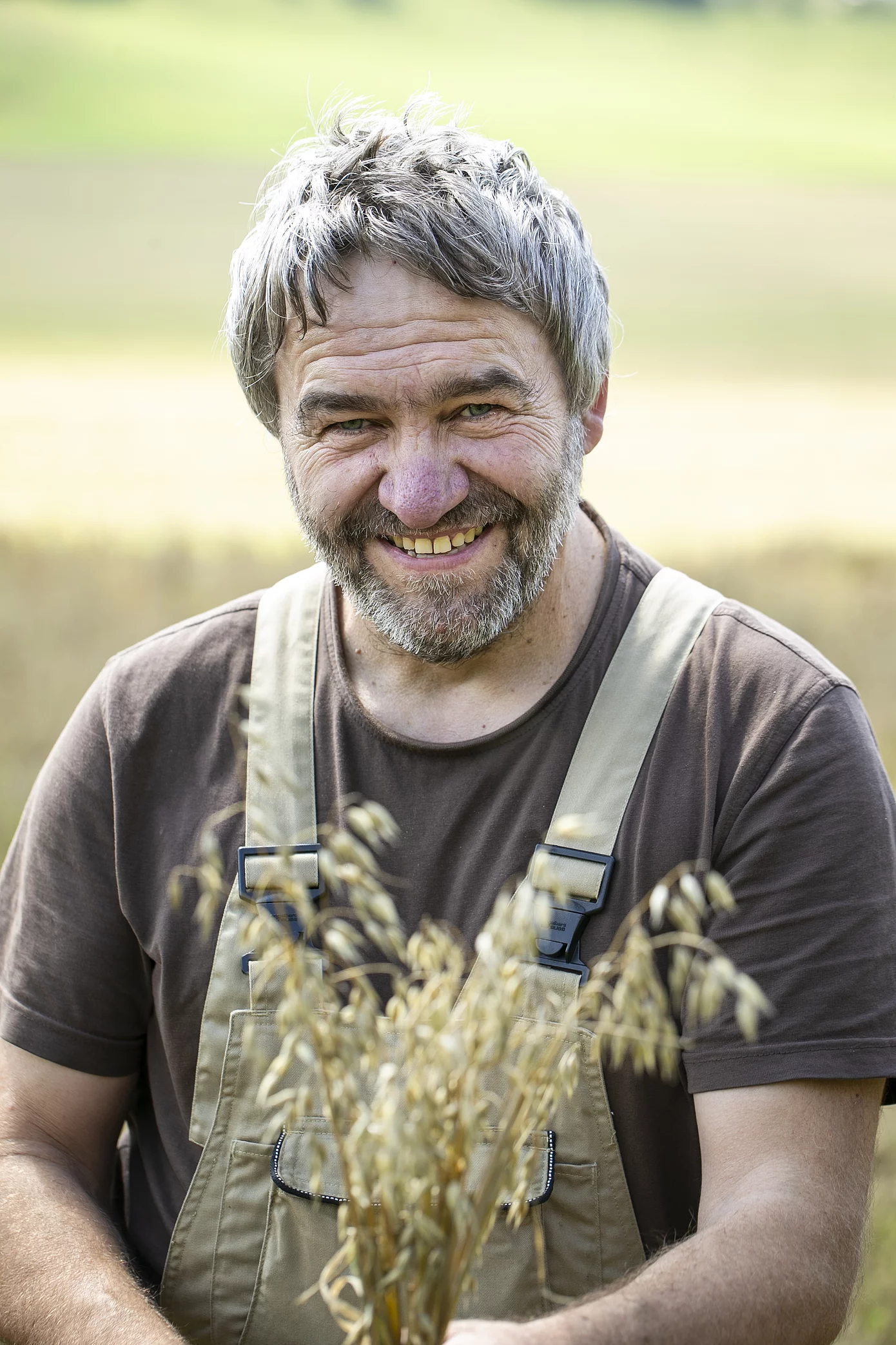 Portraitaufnahme von einem Haferbauer mit Haferhalmen in der Hand.
