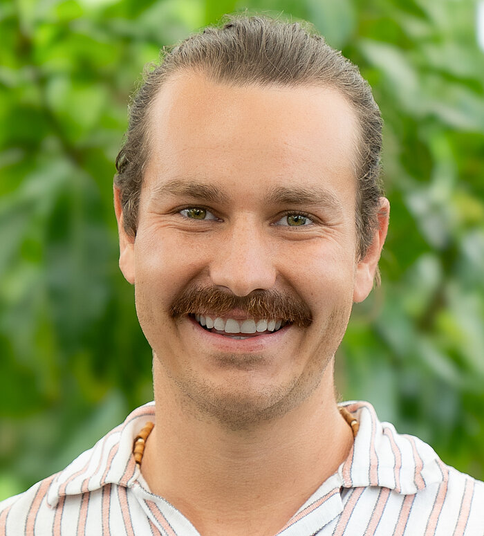 Rapunzel Mitarbeiter steht vor blühender Pflanze.