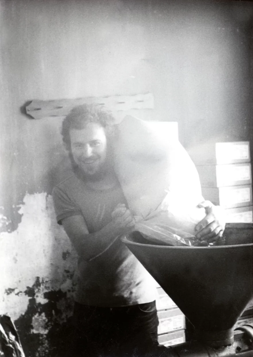 Historisches Schwarz-Weiß-Foto, das einen Mann (Joseph Wilhelm) zeigt, der einen Sack auf der Schulter trägt. 