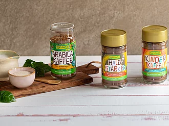 Mehrere Gläser mit Rapunzel Instant-Kaffee nebeneinander auf einem Tisch