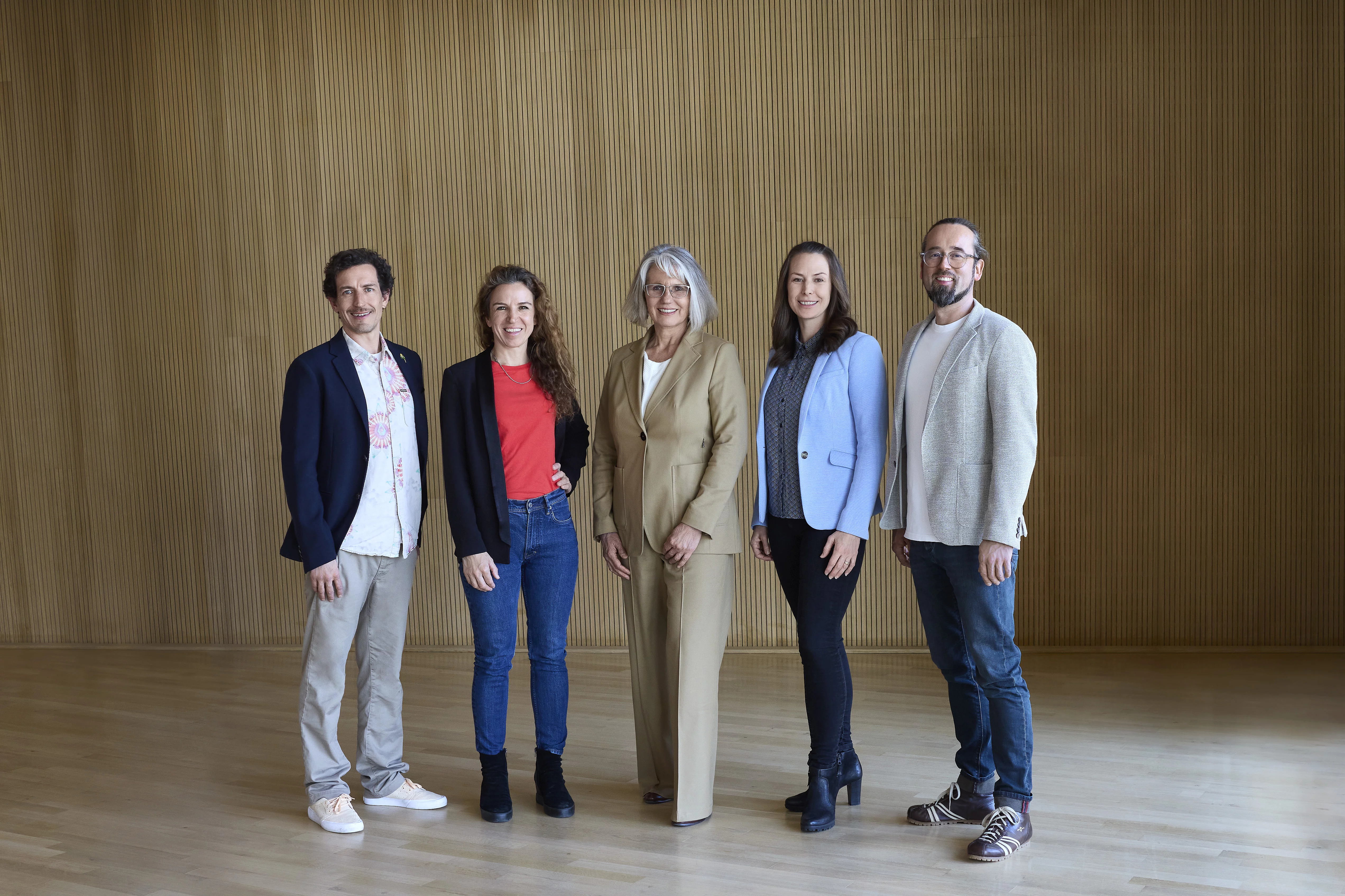 Die Rapunzel Geschäftsführung: Margit Epple, Seraphine Wilhelm, Leonhard Wilhelm, Rosalie Dorn und Werner Berlage stehen nebeneinander vor einer grauen Wand und schauen lächelnd in die Kamera