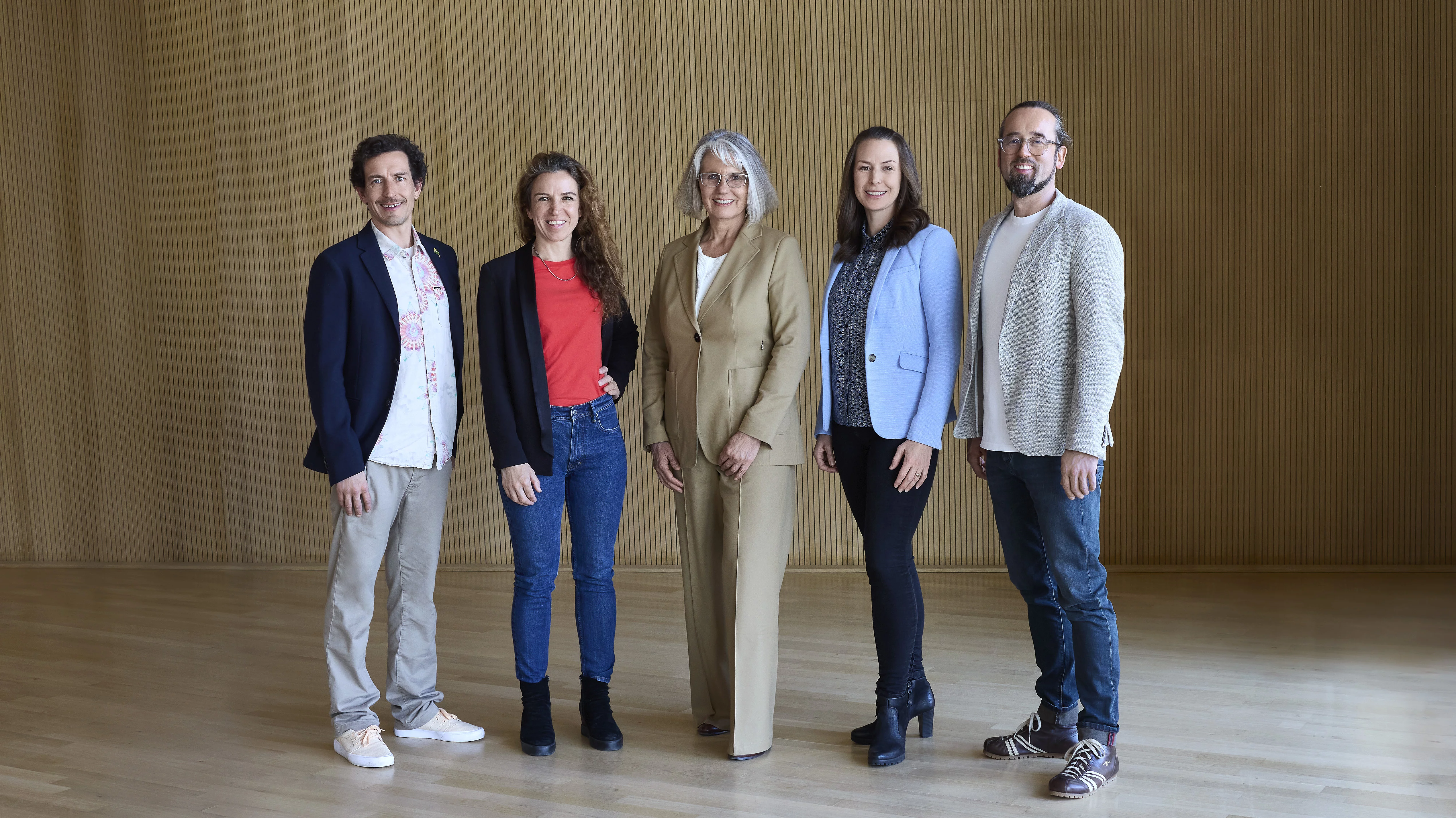 Die Rapunzel Geschäftsführung: Margit Epple, Seraphine Wilhelm, Leonhard Wilhelm, Rosalie Dorn und Werner Berlage stehen nebeneinander vor einer grauen Wand und schauen lächelnd in die Kamera