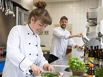 Eine Köchin und ein Koch bereiten mit Rapunzel Produkten Essen zu.