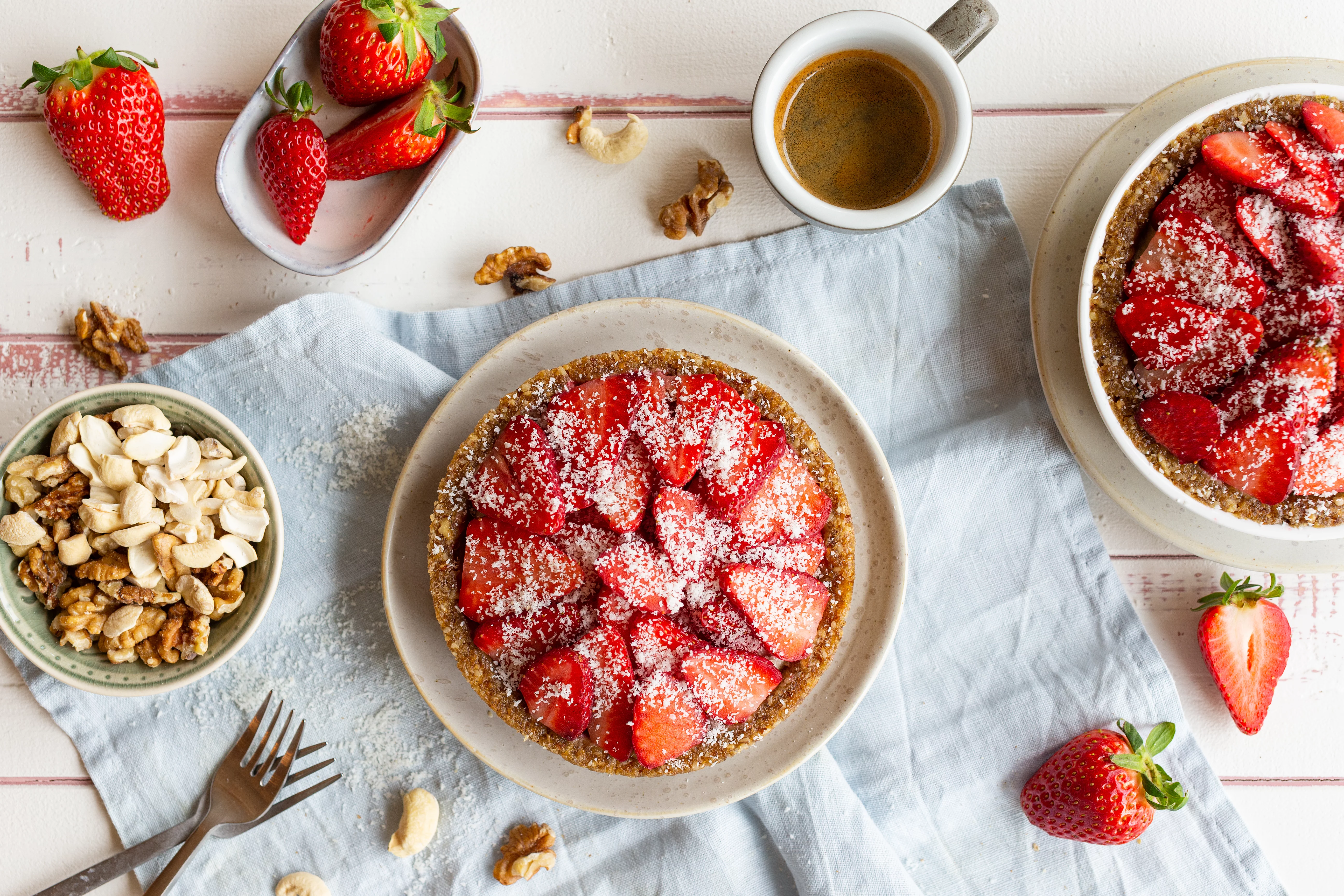 No-bake-Törtchen mit cremiger Füllung auf knusprigem Boden, belegt mit frischen Erdbeeren und Puderzucker bestäubt.