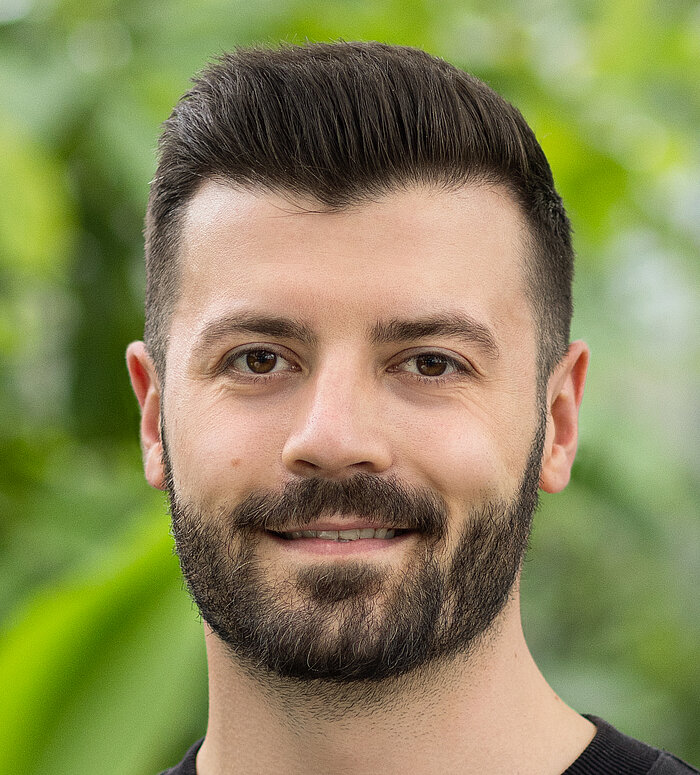 Rapunzel Mitarbeiter steht vor blühender Pflanze.