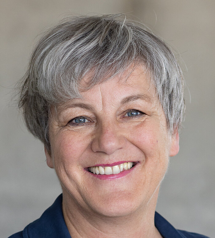 Mitarbeiterin Rapunzel Pressesprecherin vor grauer Betonwand.