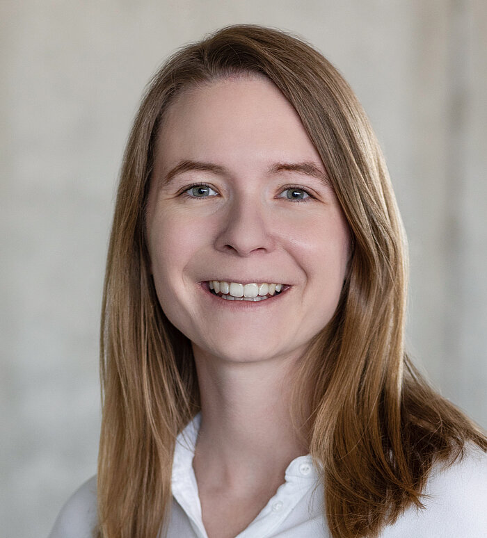 Mitarbeiterin Rapunzel Presseteam vor grauer Betonwand.