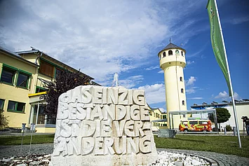 Stein mit der Schrift Das einzige beständige ist die Veränderung vor dem Firmengebäude in Legau.