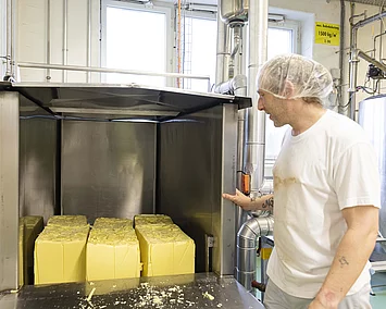 Maestrani Mitarbeiter schiebt Kakaobutter und Kakaomasse in die Schmelzöfen.