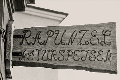 Das historische Ladenschild aus Holz mit der Aufschrift Rapunzel Naturspeisen.