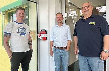 Neuer Defibrillator in Legau bei Rapunzel installiert. Stefan Schmaus, Geschäftsführer Rapunzel, Bürgermeister von Legau Thomas Heinle und der Leiter des Gebäudemanagements bei Rapunzel, Matthias Bloching mit dem neuen öffentlichen Defibrillator.