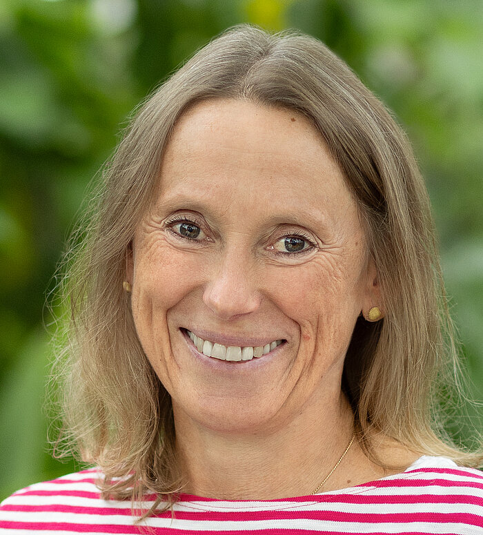 Rapunzel Mitarbeiterin steht vor blühender Pflanze.