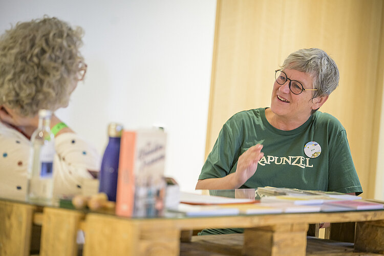 Eva Kiene, Rapunzel Pressesprecherin, sitzend an einem Glastisch und im Gespräch zu Unternehmens- und Biothemen