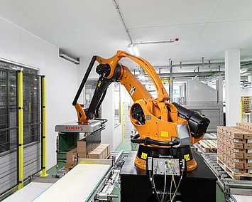 Ein Roboter stapelt die fertigen Müsli-Kartons auf eine Palette.