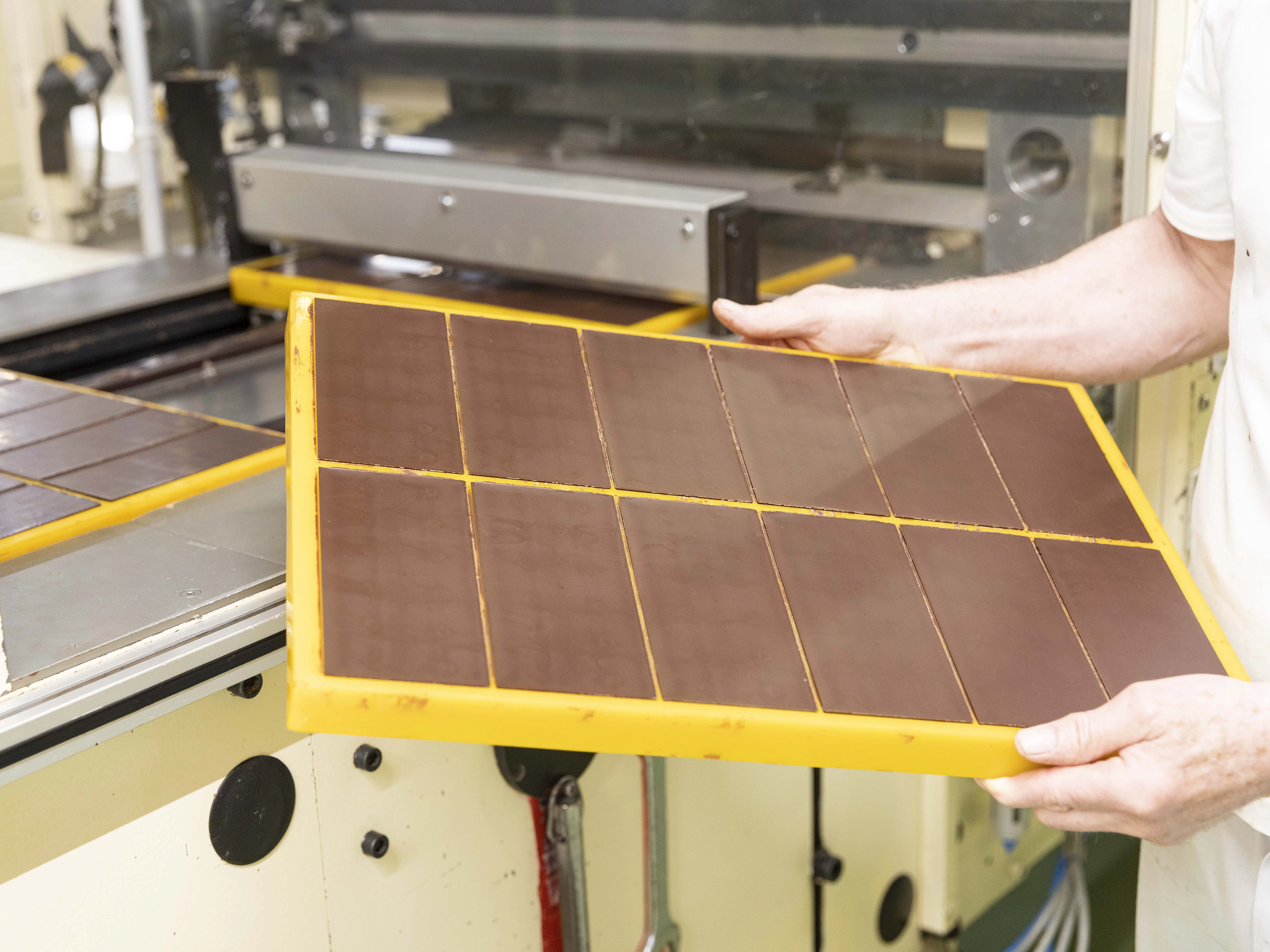 Erkaltete Schokolade in Tafelform, gehalten von einem Mitarbeiter.