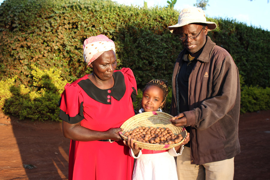 Farmer, Esther Njoki (l.), and her family proudly present a basket of their macadamia harvest.