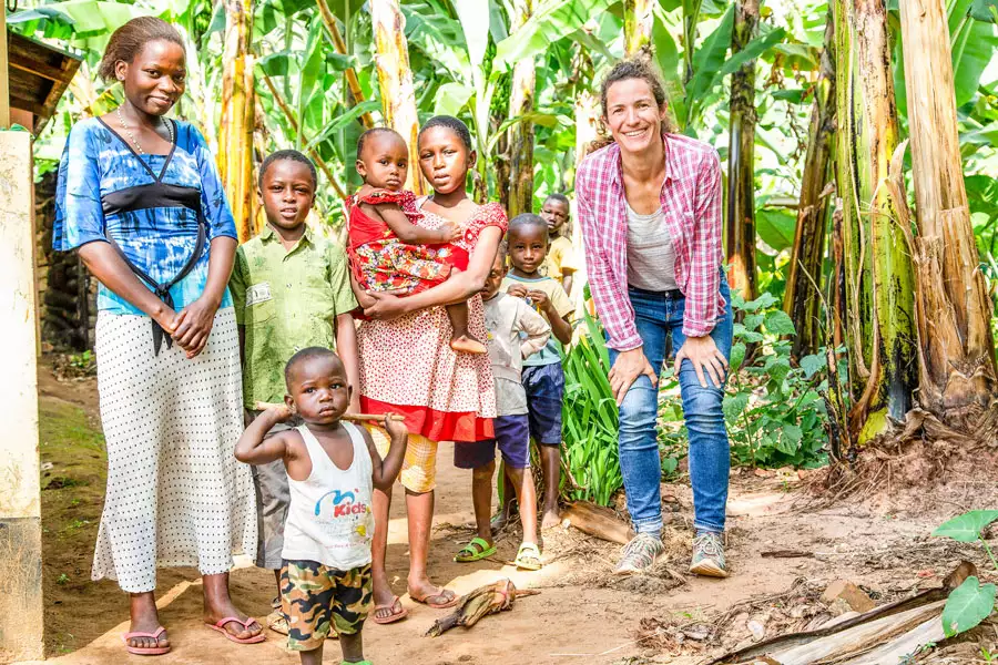 Fotografin Justina Wilhelm, Tochter von Joseph Wilhelm, und die Familie eines Anbauers vor dem Mischwald aus Bananen, Kaffee und anderen Pflanzen.