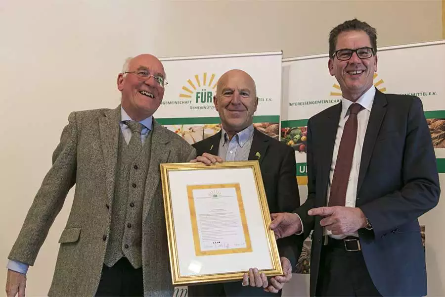 Aus der Hand von Entwicklungsminister Dr. Gerd Müller (rechts) erhielt Rapunzel Gründer Joseph Wilhelm den erstmalig verliehenen Goldenen Ehrenbrief der IG FÜR, die Georg Sedlmaier (links) gründete.