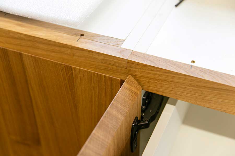 You can tell that the kitchen cabinet is made of solid oak by the continuous wood grain.