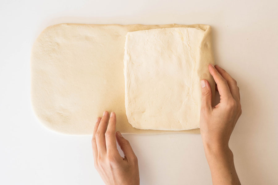 8. Die Ziehbutter auf die rechte Hälfte des Teiges legen und mit der anderen Seite bedecken. 8. Die Ziehbutter auf die rechte Hälfte des Teiges legen und mit der anderen Seite bedecken.